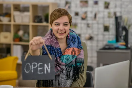 Woman holding an open sign in her business.